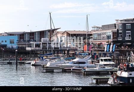 Cardiff, pays de Galles - 14 août 2022 : bateaux amarrés dans la marina moderne de Cardiff Bay avec des restaurants en bord de mer et des personnes se relaxant par une journée d'été ensoleillée Banque D'Images