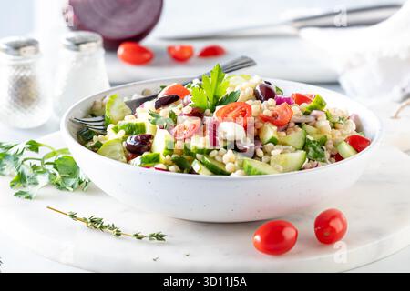 Un bol de salade de couscous israélien frais maison entouré d'ingrédients. Banque D'Images