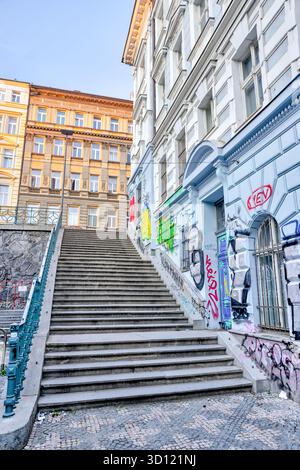 Bâtiments couverts de graffitis bordant un long escalier extérieur à Prague, République tchèque, photographiés dans la lumière du petit matin. Banque D'Images