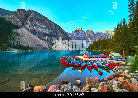 Lake Moraine Sunrise Canoe Dock Reflections et Mountain Peaks dans une eau immaculée Banque D'Images