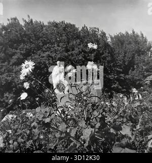 Le complexe commémoratif de la seconde Guerre mondiale avec une flamme éternelle à la KhimProm (usine chimique) à Sloviansk, dans les années 1970 Cette photo d'archives en noir et blanc de l'URSS, la RSS d'Ukraine, montre le monument de l'usine dédié à la Grande Guerre patriotique. Le mémorial présente une statue d'un soldat soviétique dans un imperméable debout sur un piédestal, avec des plaques commémoratives derrière lui. Un brûleur à flamme éternelle (non allumé) est à l'avant. Le monument est entouré d'un parterre de fleurs. Cette image capture un mémorial de guerre soviétique typique dans une entreprise industrielle. Un document de vie paisible dans le Donbass avant la guerre. Banque D'Images