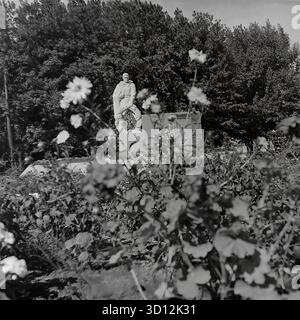 Le complexe commémoratif de la seconde Guerre mondiale avec une flamme éternelle à la KhimProm (usine chimique) à Sloviansk, dans les années 1970 Cette photo d'archives en noir et blanc de l'URSS, la RSS d'Ukraine, montre le monument de l'usine dédié à la Grande Guerre patriotique. Le mémorial présente une statue d'un soldat soviétique dans un imperméable debout sur un piédestal, avec des plaques commémoratives derrière lui. Un brûleur à flamme éternelle (non allumé) est à l'avant. Le monument est entouré d'un parterre de fleurs. Cette image capture un mémorial de guerre soviétique typique dans une entreprise industrielle. Un document de vie paisible dans le Donbass avant la guerre. Banque D'Images