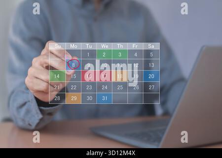 Calendrier pour les rendez-vous mensuels et la planification, gestion de son horaire d'affaires, main marquant les dates sur le calendrier virtuel Banque D'Images