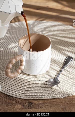 Verser du café frais dans une tasse en céramique, machine à café geyser, lumière naturelle, petit déjeuner Banque D'Images