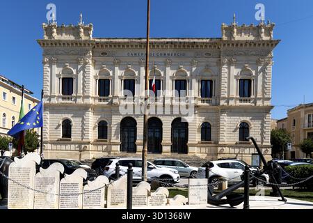 Syrakus, Sizilien - Italie - 04-09-2025 : vue de face de la Chambre de commerce de Syracuse avec drapeaux, plaques commémoratives, voitures garées et une grande ancre noire Banque D'Images