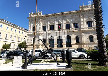 Syrakus, Sizilien - Italie - 04-09-2025 : Chambre de commerce historique à Syracuse avec façade ornée, drapeau italien, voitures garées, grande ancre et marit Banque D'Images