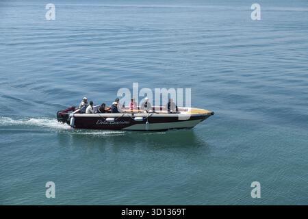 Syrakus, Sizilien - Italie - 04-09-2025 : petit bateau à moteur avec plusieurs passagers naviguant sur des eaux bleues calmes à Syracuse, vu de côté avec gent Banque D'Images