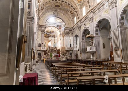 Bosa - Sardinien - Italien - 02-28-2025 : vue intérieure latérale d'une église baroque richement décorée montrant des bancs en bois, plafond voûté, autel orné, a Banque D'Images