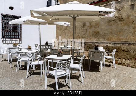 Cordoue, Cordoue - Espagne - 04-08-2024 : un café en plein air avec des tables couvertes de parasols blancs, installé contre un mur de pierre historique à Cordoue Banque D'Images