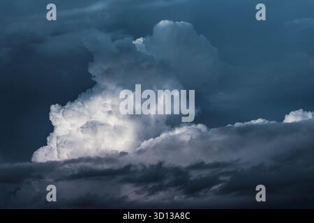 Grand cumulonimbus bâtiment de nuages dans un ciel sombre. La lumière du soleil illumine des parties du nuage tandis que d'autres restent profondément dans l'ombre Banque D'Images