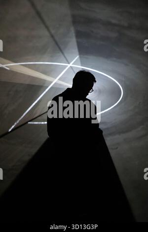 Silhouette contre motifs lumineux géométriques dans une installation abstraite. Banque D'Images
