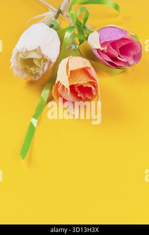 Fleurs en papier ondulé maison sur fond jaune Banque D'Images