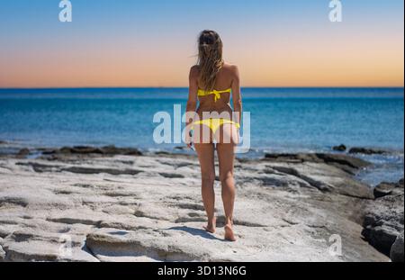 la femme regarde le beau coucher de soleil sur la mer bleue Banque D'Images