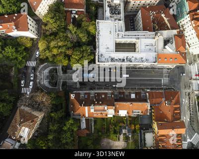 Vue aérienne du cœur d'une ville où le vert vibrant des arbres rencontre les toits en terre cuite, séparés par une route droite menant à une fontaine monumentale, Trieste, Frioul-Vénétie Julienne, Italie. Banque D'Images
