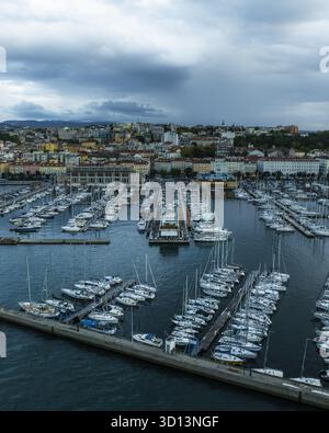 Vue aérienne des yachts et des bateaux nichés dans la marina, une symphonie de blanc contre la mer bleu profond sous un ciel dramatique, Trieste, Frioul-Vénétie Julienne, Italie. Banque D'Images