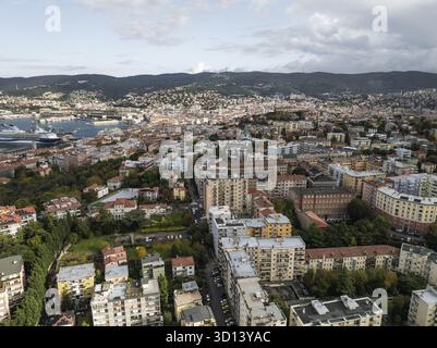 Vue aérienne des bâtiments de la ville et du port, où les toits en terre cuite rencontrent l'Adriatique, sous un ciel faisant allusion aux montagnes au-delà, Trieste, Frioul-Vénétie Julienne, Italie. Banque D'Images