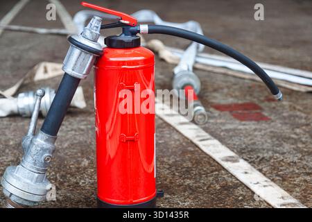 Cylindre d'extincteur rouge avec tuyaux d'incendie déroulés. Banque D'Images