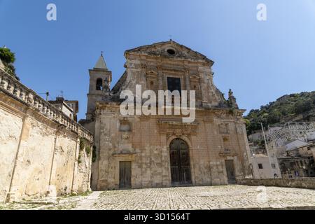 Scicli, Sizilien - Italie - 04-05-2025 : façade de l'église Santa Maria della Consolazione à Scicli, avec murs en pierre usés, grandes portes en bois, cloche Banque D'Images