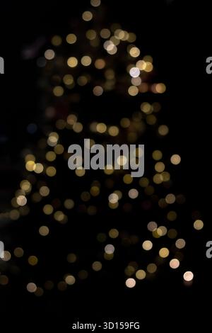 Des lumières bokeh dorées douces créent une lueur festive sur fond sombre Banque D'Images