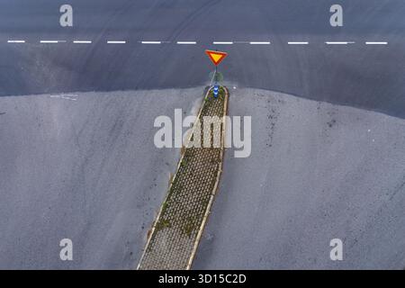 Vue de dessus d'une intersection avec un panneau de rendement et des marquages routiers. Banque D'Images