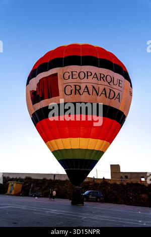Guadix, Grenade - Espagne - 2024 : une montgolfière colorée avec Geoparque Granada en rouge, noir et jaune est prête à monter sous un ciel bleu Banque D'Images