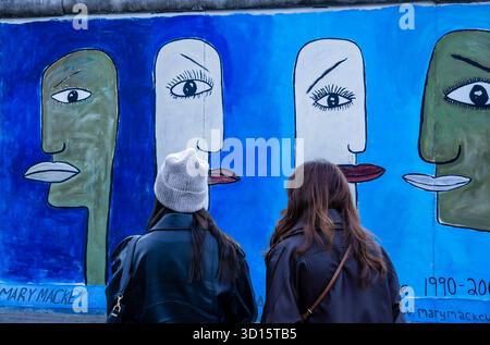 Deux femmes debout devant la East Side Gallery, la célèbre galerie en plein air sur les vestiges du mur de Berlin. Touristes, Tourisme de ville. Banque D'Images