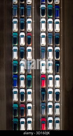 Une vue aérienne directement au-dessus de rangées de voitures nouvellement construites dans l'industrie automobile sur un quai commercial prêt à être chargé pour l'exportation et l'importation Banque D'Images