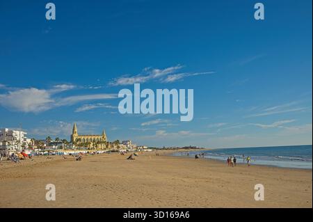 Plage de Regla avec église et phare à Chipiona dans la lumière chaude du soir Banque D'Images