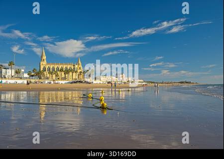 Plage de Regla avec église et phare à Chipiona dans la lumière chaude du soir Banque D'Images