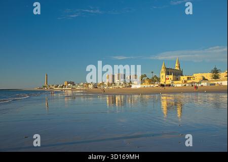 Plage de Regla avec église et phare à Chipiona dans la lumière chaude du soir Banque D'Images