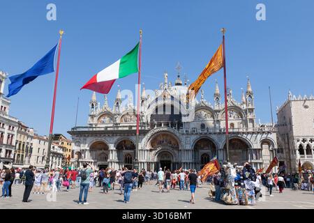 Drapeaux flottant des mâts de drapeaux devant la Basilique Saint Marc, Piazza San Marco pendant la fête de Saint Marc, saint patron de Venise, Italie Banque D'Images