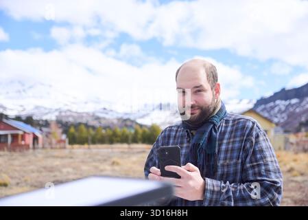 Homme se connectant au Wi-Fi à partir d'un village éloigné en utilisant une antenne Internet par satellite. La technologie permet aux voyageurs de rester connectés tout en voyageant. Banque D'Images