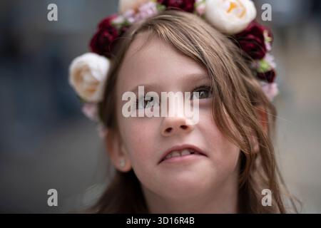 Portrait rapproché d'une fille ukrainienne souriante dans une blouse brodée et une couronne florale regardant vers le haut, concept de joie d'enfance et de tradition ukrainienne. Banque D'Images