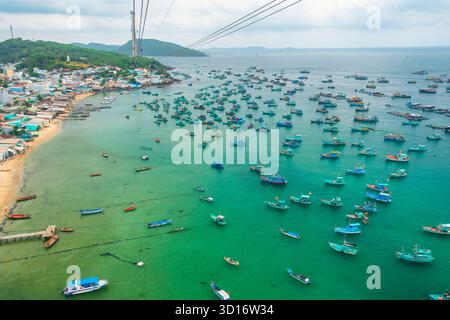 Vue aérienne de bateaux de pêche colorés ancrés dans les eaux turquoises près du village côtier de l'île de Phu Quoc, Vietnam avec le plus long trajet en téléphérique dans le Banque D'Images