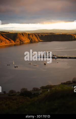 Vue aérienne du port d'Uig sur l'île de Skye, en Écosse, au coucher du soleil avec une lumière dorée traversant des nuages d'humeur sombre au-dessus du Loch Snizort. Banque D'Images