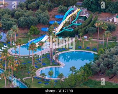 Superbe perspective de drone aérien d'un luxueux complexe de vacances méditerranéen. Les caractéristiques comprennent un parc aquatique animé, des piscines sereines, des chaises longues, Banque D'Images