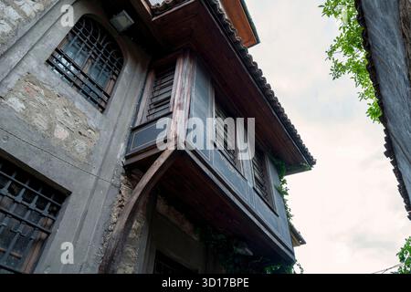 Vue vers le haut d'une maison de style renaissance bulgare dans la vieille ville de Plovdiv, dotée d'une baie vitrée en bois et de murs en pierre avec des fenêtres en fer. Banque D'Images
