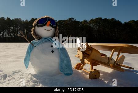 Bonhomme de neige portant un chapeau festif à l'extérieur. Homme de neige heureux dans le paysage froid d'hiver. Bonhomme de neige avec bannière hivernale glacée. Bonhomme de neige avec foulard ondulant. Banque D'Images