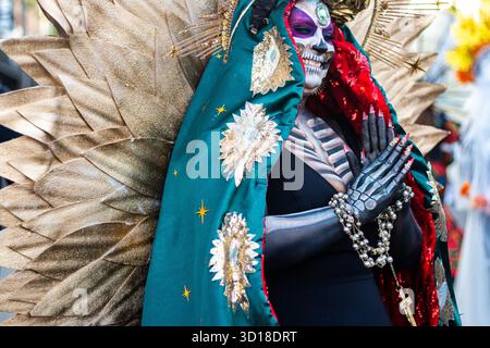 Los Angeles, États-Unis. 26 octobre 2025. Une femme habillée en squelette, connue sous le nom de Catrina, sourit et fait des vagues à un ami dans la foule lors de la célébration du Dia de los Muertos à San Pedro, Los Angeles, Californie. Crédit : Stu Gray/Alamy Live News. Banque D'Images