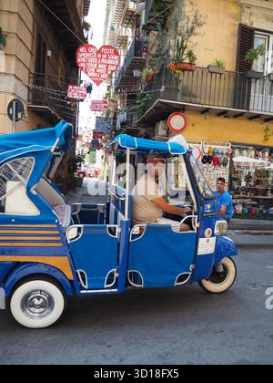 Taxi bleu à trois roues dans une rue animée avec des décorations suspendues à Palerme Sicile Banque D'Images