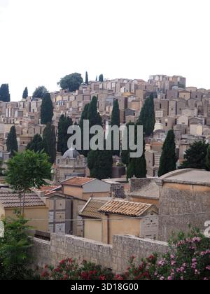 Cimetière sur la colline à Enna, Sicile, Italie, avec des cyprès et de vieux mausolées de pierre sous le ciel nuageux Banque D'Images