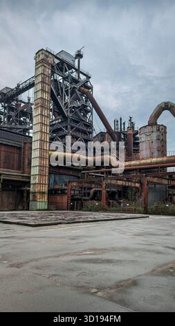 Ancienne usine industrielle avec structures métalliques rouillées, tuyaux et cheminée. Banque D'Images