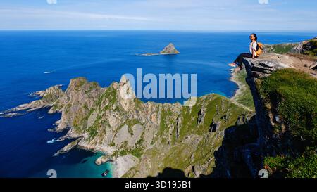 Découvrez le magnifique panorama depuis la montagne Matind à Andoya, en Norvège. Un randonneur seul profite de la vue imprenable sur les falaises spectaculaires et l'océan bleu scintillant en contrebas. Banque D'Images