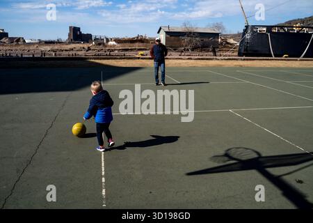 Garçon tout-petit et père jouant avec le basket-ball sur un court extérieur Banque D'Images