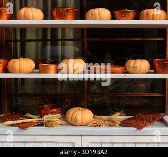 Vitrine décorative devant un magasin de village, décorée avec des ustensiles de cuisine en cuivre de style rétro et des citrouilles mûres cultivées à la maison Banque D'Images