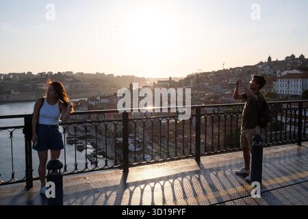 Vue d'une personne prenant une photo du coucher de soleil sur Porto depuis le pont Dom Luis I, au nord du Portugal, le 8 mai 2022. La scène capture l'urbain la Banque D'Images