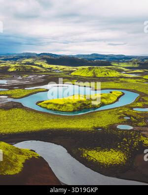 Vue aérienne de collines verdoyantes reflétées dans les eaux calmes et bleues, contrastant avec la terre sombre, Langisjór, Skaftárhreppur, Islande. Banque D'Images