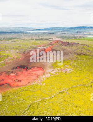 Vue aérienne d'un paysage volcanique rouge saisissant contrastant avec la végétation verte vibrante environnante, Heydalsvegur, Islande. Banque D'Images