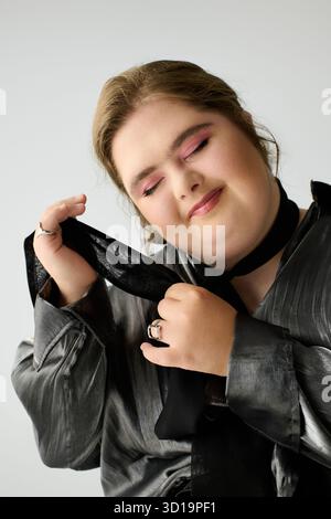 Femme avec le syndrome de Down exprime le bonheur tout en jouant avec une écharpe à l'intérieur. Banque D'Images