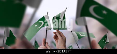 Drapeaux pakistanais dans leurs mains sur un fond urbain flou. L'illustration photo a été créée sans l'utilisation de l'intelligence artificielle, uniquement en utilisant Photoshop. Banque D'Images